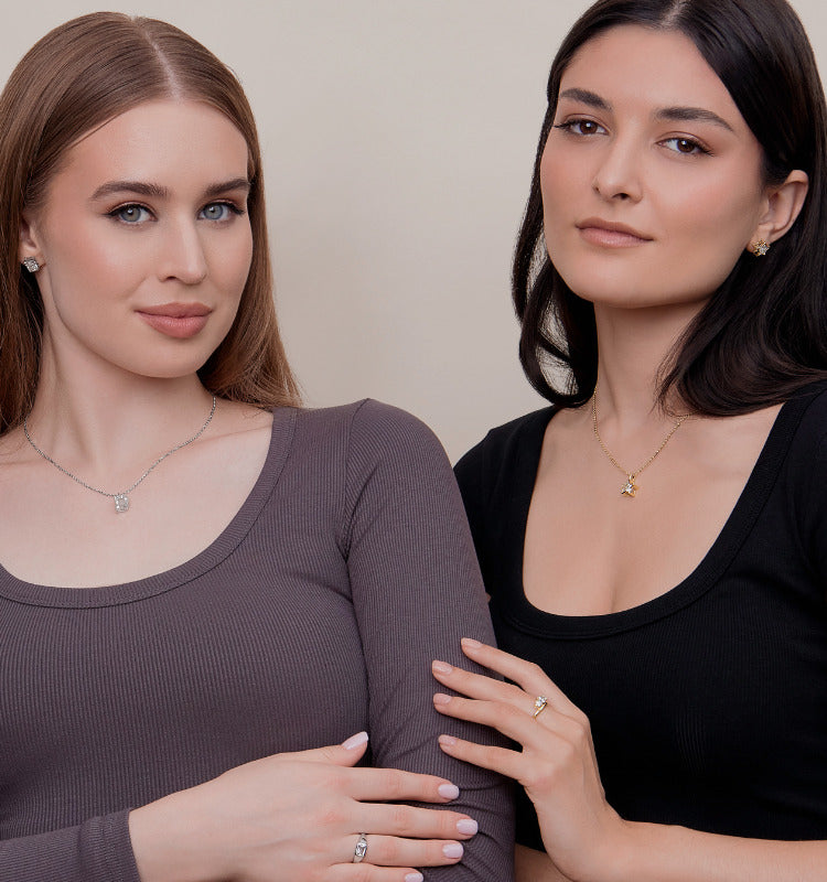 Two women wearing necklaces against a neutral background wearing jewelry